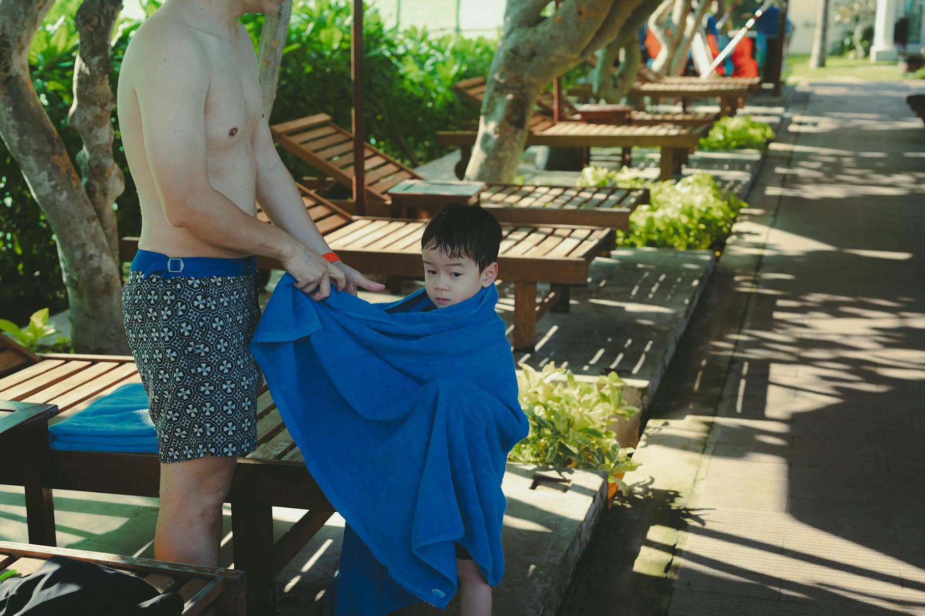 Ojciec owija syna ręcznikiem na plaży przy rodzinnym resorcie