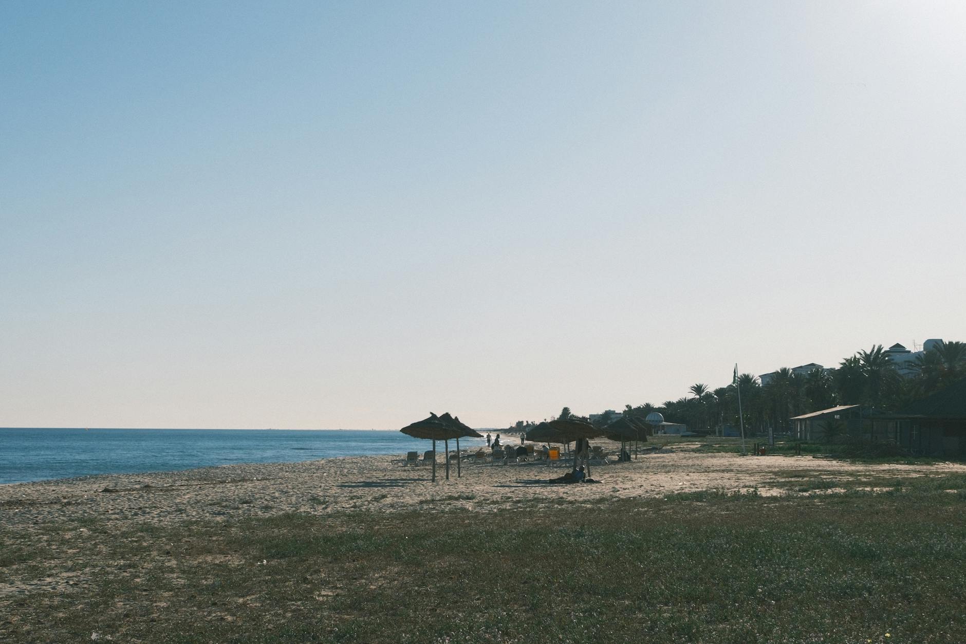 Spokojna tunezyjska plaża o zachodzie słońca z parasolami z trzciny