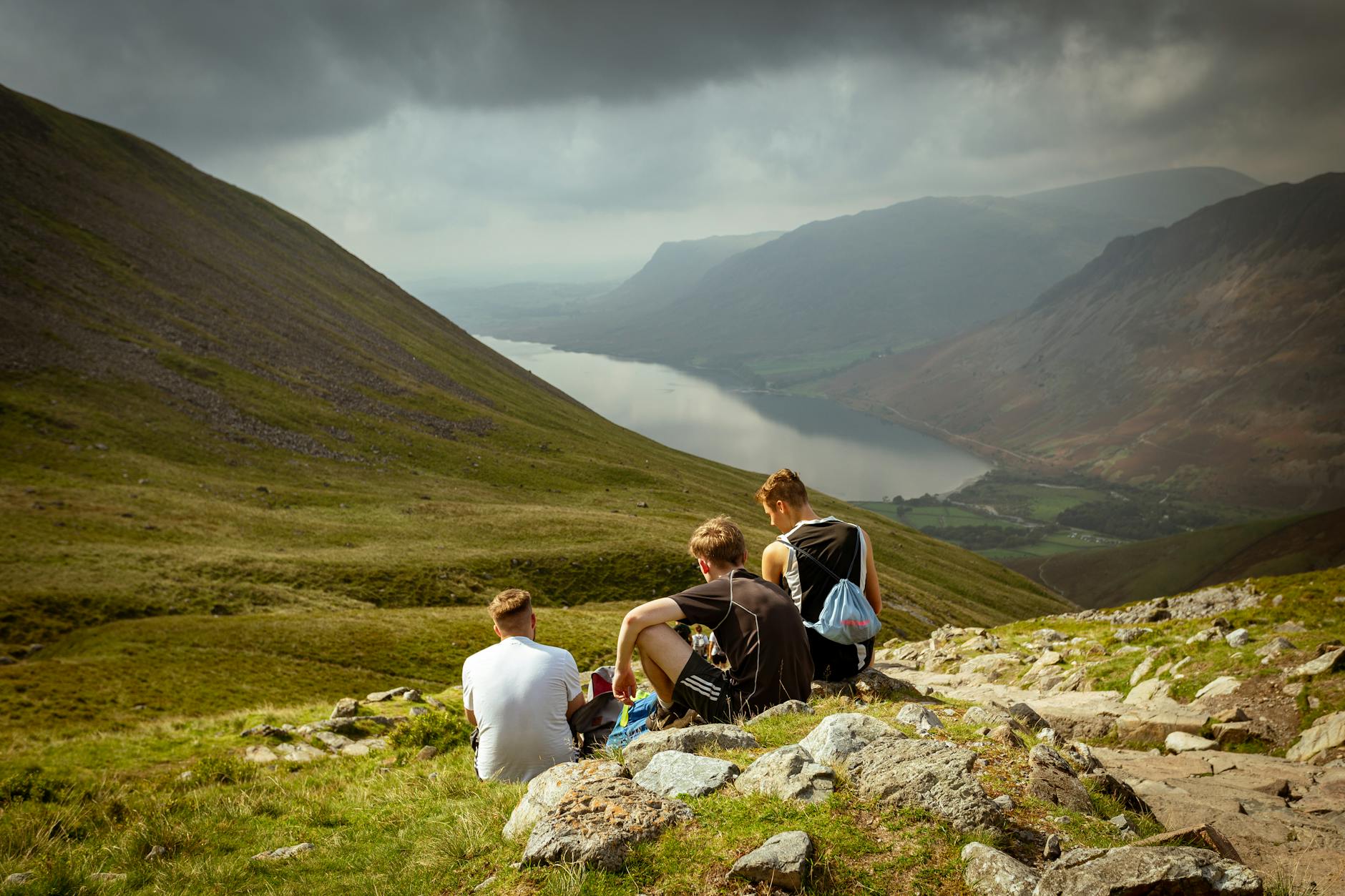 Trzech młodych mężczyzn podziwia jezioro Wasdale otoczone górami