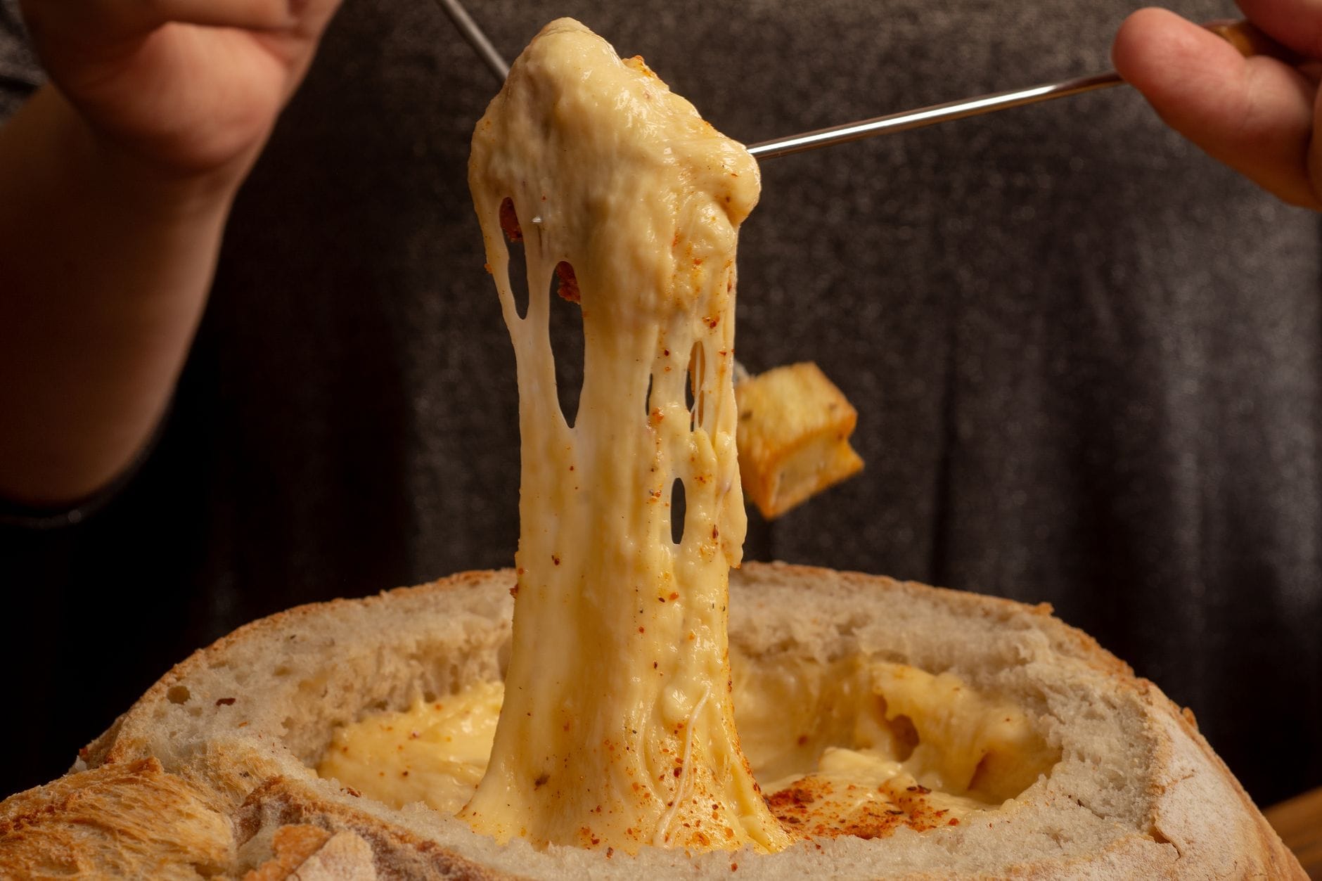 Ciągnące się szwajcarskie fondue serowe nabierane z miski chleba